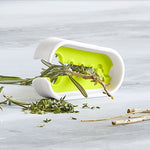 Herb remover with fresh herbs on a light gray background.