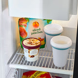 Refrigerator interior with a container of sliced peaches, yogurt, and two cups.