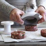 Person using a hamburger press to shape into even patties.