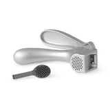 Silver garlic press with a small black container on a white background