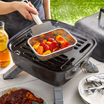 Person grilling vegetables on a portable grill outdoors