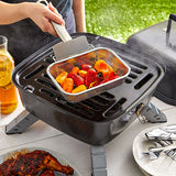 Person grilling vegetables on a portable grill outdoors
