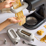 Pasta maker being used to create pasta on a marble countertop.
