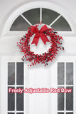 Red berry wreath with a freely adjustable red bow on a white door.