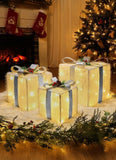 Decorative Christmas scene with lit presents, tree, and stockings by a fireplace.