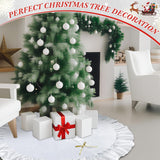 Decorated Christmas tree with white ornaments and presents in a living room.