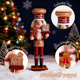 Wooden nutcracker figure with gingerbread man, house, and cylinder hat details, Christmas tree in background.