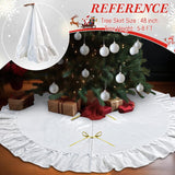 White Christmas tree skirt with ruffles in front of a decorated Christmas tree.