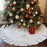 Decorated Christmas tree with ornaments and a present underneath, covered by a white tree skirt.