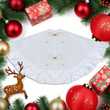 White Christmas tree skirt with gold ribbons surrounded by festive decorations on a white background
