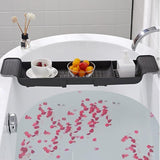 Bath tub with a black bathtub tray holding a cup, saucer, and bowl of fruit, surrounded by pink bath petals.