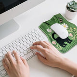Person using a keyboard with a green knitted mouse pad featuring a black cat design.