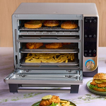 Deluxe Air Fryer and Toaster Oven with food items inside, on a table.