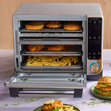 Deluxe Air Fryer and Toaster Oven with food items inside, on a table.