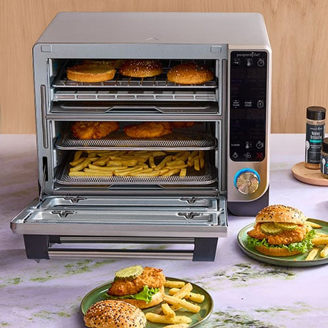 Deluxe Air Fryer and Toaster Oven with food items inside and on a table.