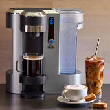 Coffee maker machine with a cup of coffee, glass of iced coffee, and a plate with a cup of cappuccino on countertop   surface.
