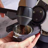 Hand using a manual coffee grinder to grind coffee beans.