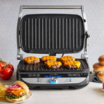 Deluxe Electric Countertop Grill and Griddle with cheeseburgers cooking on a countertop with ingredients around.