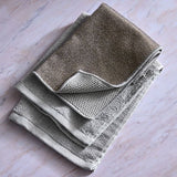 Stack of folded, dual-sided microfiber, gray towels on a marble surface.