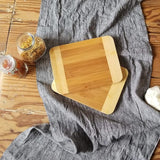 Two wooden cutting boards on a gray cloth with jars of spices in the background.