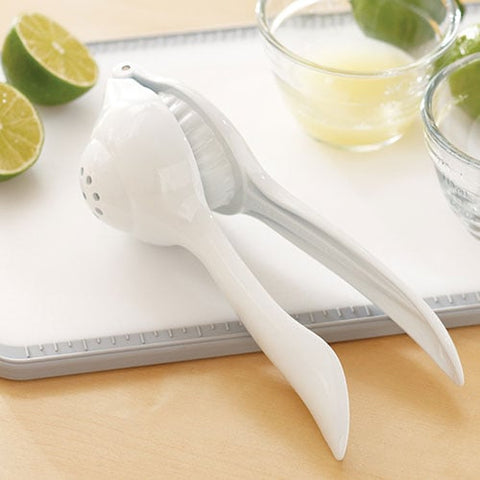 White Citrus Press on a cutting board with limes and glasses in the background.