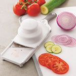 Handheld food mandoline with sliced vegetables on a cutting board.