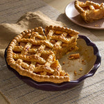 Homemade, apple pie in an Italian Plum colored Stoneware Pie Plate with a slice to the side on a serving plate.