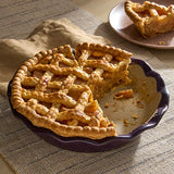 Homemade, apple pie in an Italian Plum colored Stoneware Pie Plate with a slice to the side on a serving plate.
