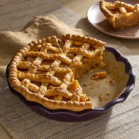 Homemade, apple pie in an Italian Plum colored Stoneware Pie Plate with a slice to the side on a serving plate.