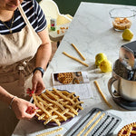 Person making pasta on a stoneware pie plate with kitchen tools and ingredients.