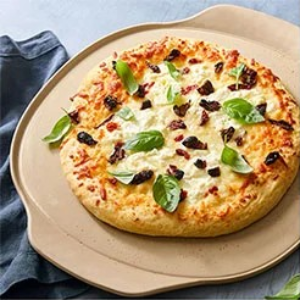 Pizza with basil on a large round pizza stoneware. 