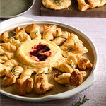 Baked brie with cranberry sauce surrounded by croissants on Large Round Pizza Stoneware Dish.