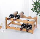 Bamboo wooden wine rack holding bottles with a plant and glasses in the background.