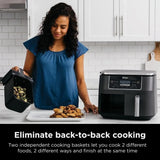 Ninja Dual Basket Air Fryer with person holding one of the air fryer baskets with food inside.