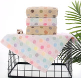 Stack of polka dot towels on a black wire basket with a green leafy plant in the background.