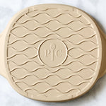 Round beige personal pizza stoneware with wavy patterns on a white background.