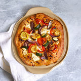 Veggie pizza with various toppings on a personal-sized, round, pizza stoneware.