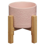 Pink ceramic planter pot with bamboo stand on a white background.
