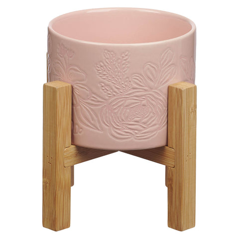 Pink ceramic planter pot and bamboo stand on a white background.