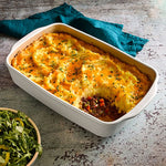 Shepherd's pie in a white, rectangular stoneware baking and serving dish on a textured surface with a green napkin.