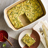 Zucchini bread in a rectangular stoneware baking and serving dish with a slice on a plate, accompanied by a bowl of red sauce.