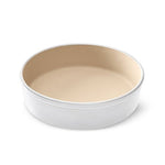 Round baking pan with beige interior on a white background.