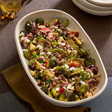 Vegetable salad with brussels sprouts, and nuts in a white ceramic serving dish.