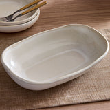 White ceramic dish on a wooden table with a textured placemat.