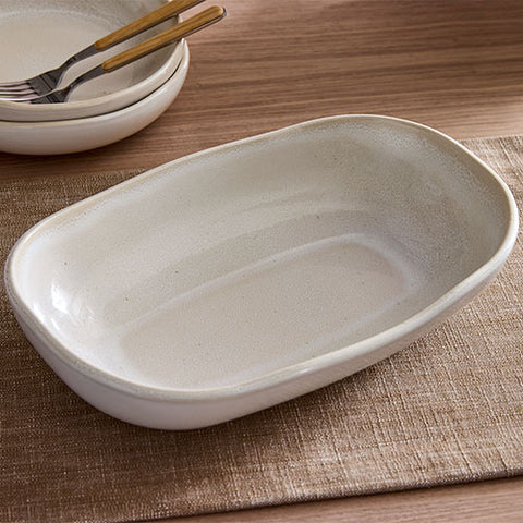 White ceramic dish on a wooden table with a textured placemat.