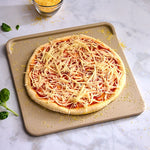 Unbaked pizza with cheese on a baking tray on a marble surface