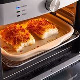 Two pieces of breaded fish cooking in an oven on a stoneware bar pan.