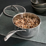 Stainless steel pot with rice on a dark surface with green placemats.