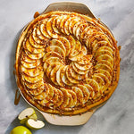 Apple tart with sliced apples on a stoneware dish.