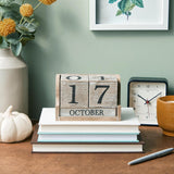 Wooden calendar showing October 17th on a desk with books, a clock, and decorative items.